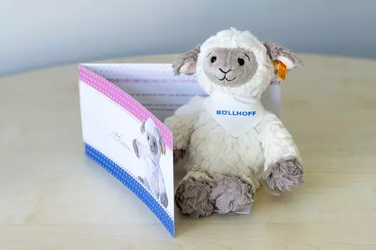 The Böllhoff cuddly toy "Lita Lamb" sits on a table with a congratulations card.