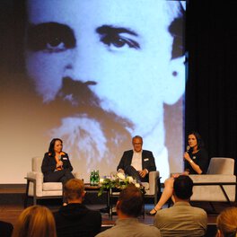 Three people sitting on a stage