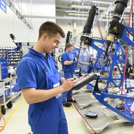 Photo of a Böllhoff apprentice inspecting a technical system