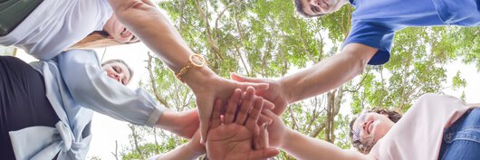 Böllhoff employees stand in a circle and place one hand on top of the other