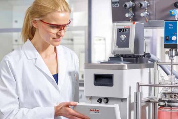 Woman with protective goggles working on a JULABO device.