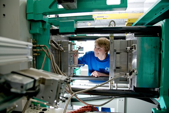 Photo of a Böllhoff apprentice inspecting an injection moulding machine