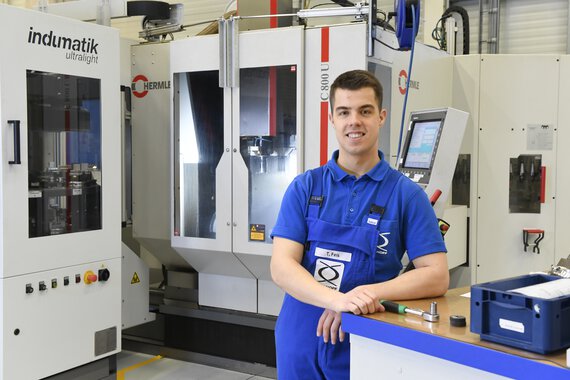 Photo of a Böllhoff apprentice next to technical equipment