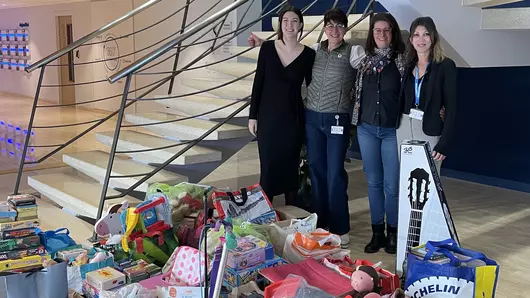 The colleagues from France stand in front of many donated gifts with toys.