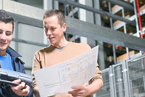 eine Böllhoff Mitarbeiter in Absprache mit einem Kollegen am Logistikstandort Oelsnitz