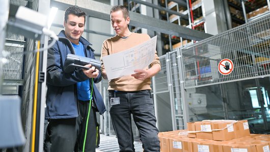 eine Böllhoff Mitarbeiter in Absprache mit einem Kollegen am Logistikstandort Oelsnitz