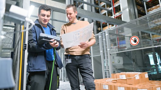 eine Böllhoff Mitarbeiter in Absprache mit einem Kollegen am Logistikstandort Oelsnitz