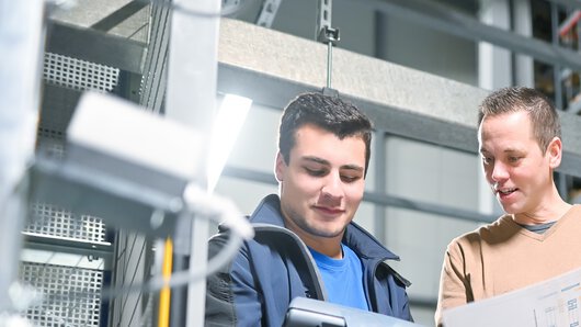 eine Böllhoff Mitarbeiter in Absprache mit einem Kollegen am Logistikstandort Oelsnitz