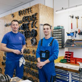 Ein Auszubildender und der Ausbilder stehen in der Werkstatt zusammen.