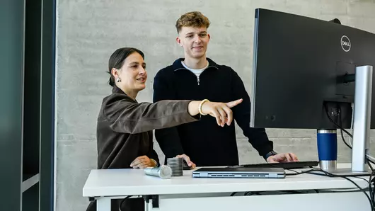 Zukunft gemeinsam gestalten: Eine Ausbilderin vermittelt einem Auszubildenden Know-how am modernen Arbeitsplatz.