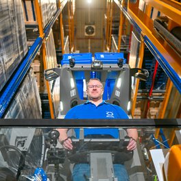 Ein Böllhoff Mitarbeiter sthet auf einem Gabelstapler im Hochregallager