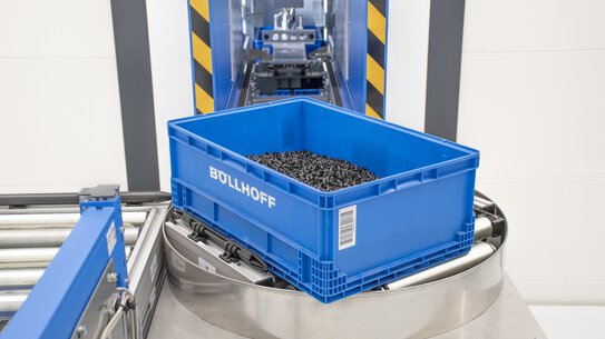 A container with raw parts is automatically removed from a storage system in the Böllhoff assembly manufacturing in Bielefeld.