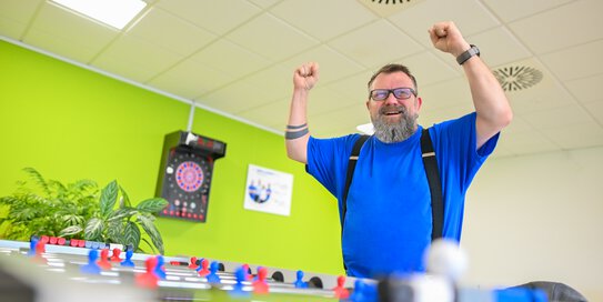 Ein Böllhoff Mitarbeiter steht mit einer Siegespose an einem Tischkicker