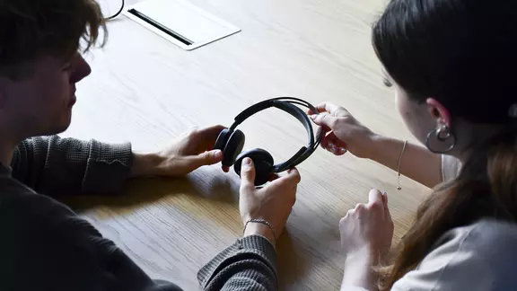 Mirando sobre los hombros de dos aprendices de Böllhoff que participan en el proyecto Exploradores de energía 2024 con unos auriculares para ordenador en las manos