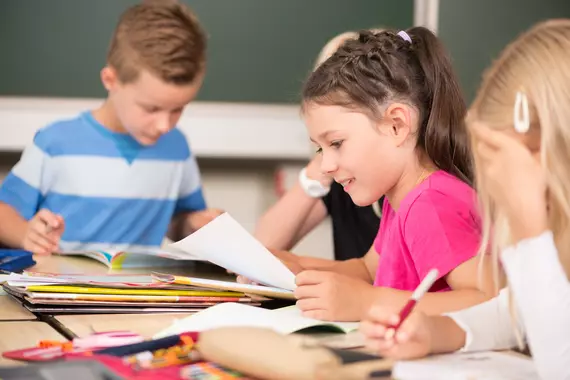 A group of primary school pupils practising reading and writing.