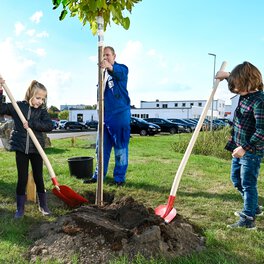 Zwei Mitarbeiterkinder schaufeln Erde an einen neu gepflanzten Baum bei der Böllhoff Baumpflanzaktion 2022.