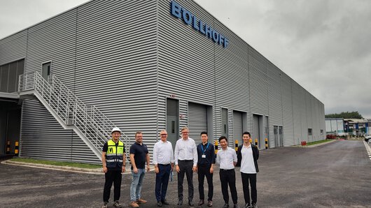 Seven Böllhoff employees stand in front of the new production building at the Chinese Böllhoff site in Wuxi shortly before its commissioning.