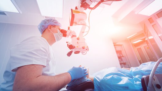 A patient and surgeon in the operating room during ophthalmic surgery.