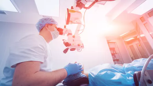A patient and surgeon in the operating room during ophthalmic surgery.