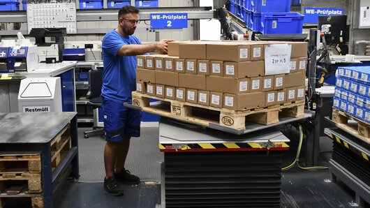 Funcionário na mesa de trabalho elevatória no departamento de entrada de mercadorias da Böllhoff