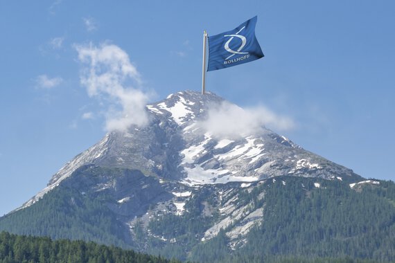 Dağın zirvesinde Böllhoff bayrağıyla dağ panoraması