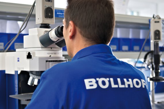 A Böllhoff employee uses a microscope to check the product quality of a fastener