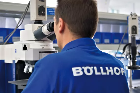 Một nhân viên Böllhoff sử dụng kính hiển vi để kiểm tra chất lượng đinh tán