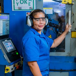 a Böllhoff employee stands at a machine and smiles into the camera