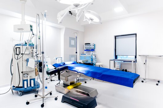 Prázdný operační sál, detaily přístrojů na podporu života, operační stůl, světla a lékařské vybavení.