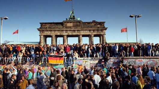 East and West Berliners celebrate the fall of the Berlin Wall in front of the Brandenburg Gate.