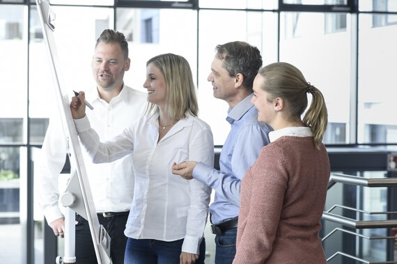 Employees stand around a flipchart