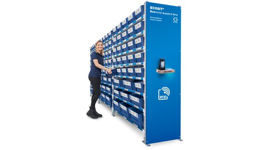 Uma mulher em pé no centro de controle de um sistema ECOSIT® está pegando uma Kanban ECOBIN.