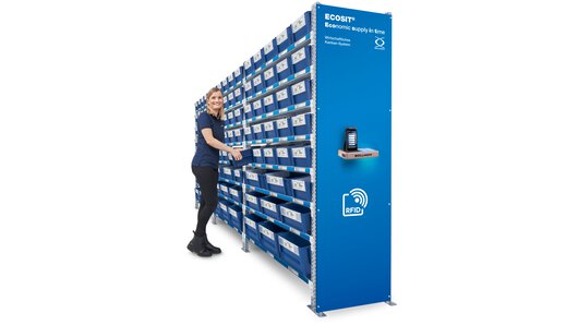 A woman standing at the control centre of an ECOSIT® system is reaching for a Kanban ECOBIN.