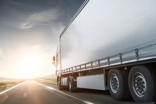 A truck driving towards sunset on a road