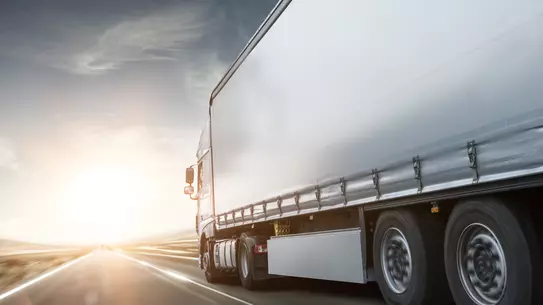 Ein LKW fährt auf einer Straße richtung Sonennuntergang